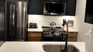 A modern kitchen with black cabinets, stainless steel appliances, and a white countertop. - Cozy 2BR Apt in Arlington, VA. Minutes from  Washington D.C. (Arlington)