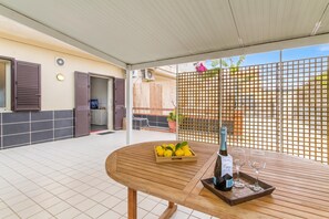 A covered patio with a wooden table, a bottle of wine, and glasses on a tray. - Distefano House Close To Sea (Ragusa)