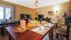 A dining area with a wooden table set for breakfast, including croissants, fruit, and orange juice. - Villa Sant'elene (Uri)