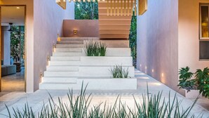 A modern staircase with a minimalist design, surrounded by indoor plants and a well-lit environment.