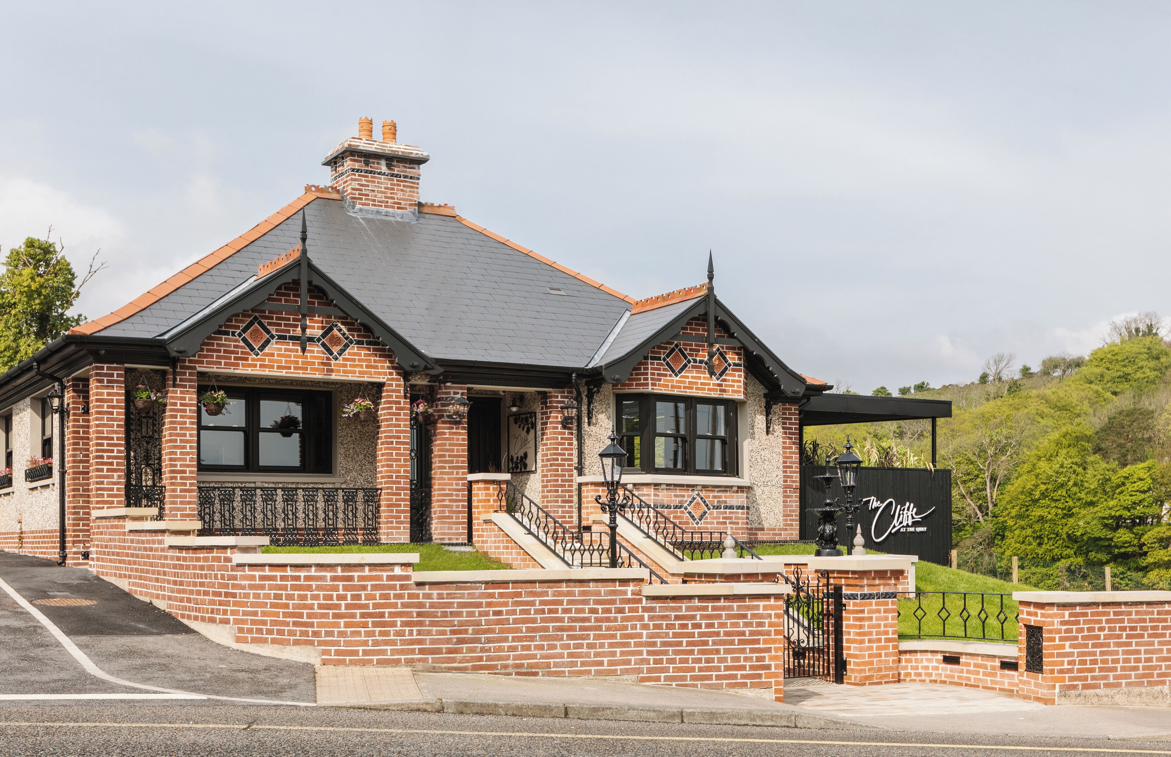 Ein Haus aus Backsteinen mit Satteldach, Schornstein und einer kleinen Veranda mit Stufen.