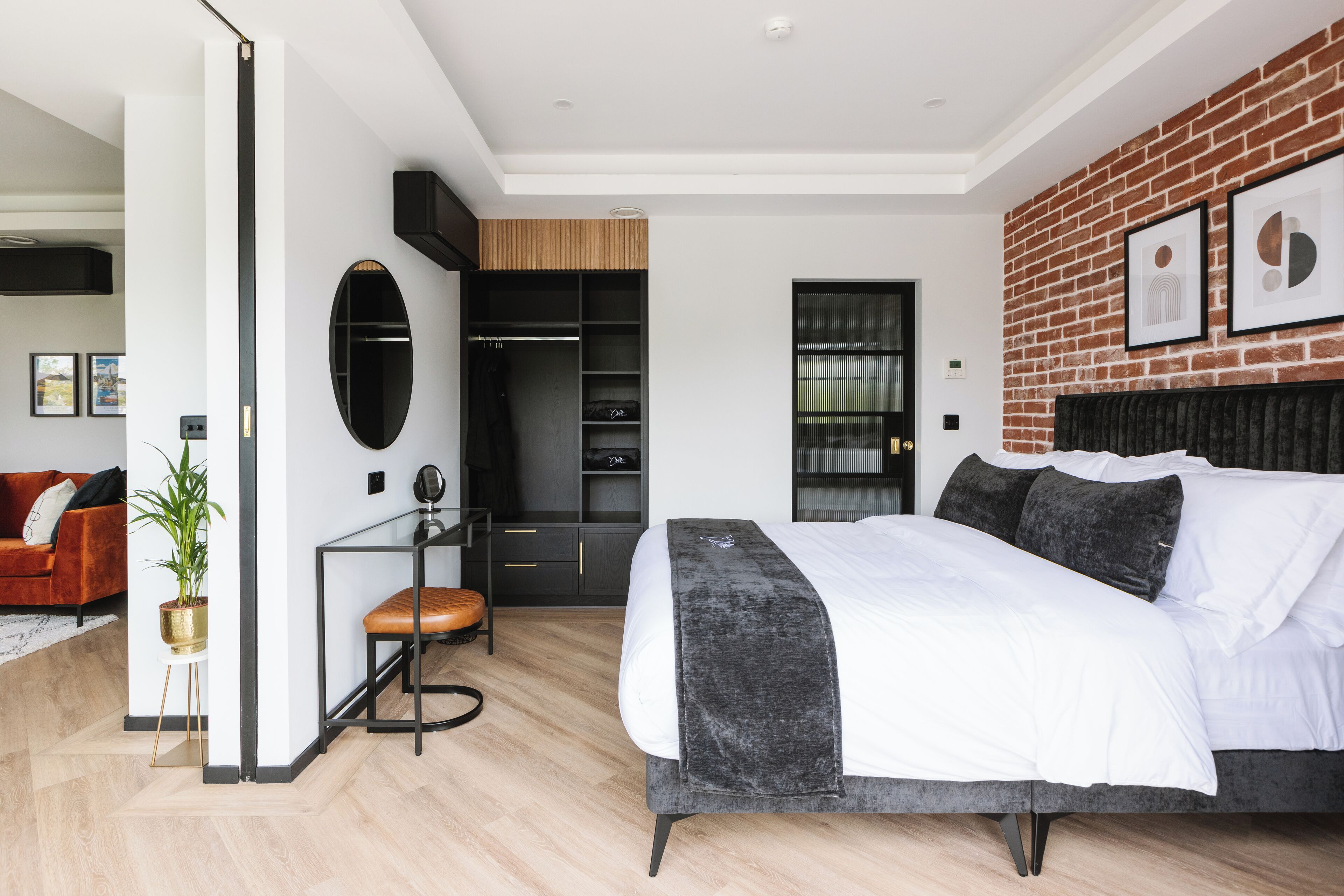 A modern bedroom with a large bed, a closet, and a seating area.