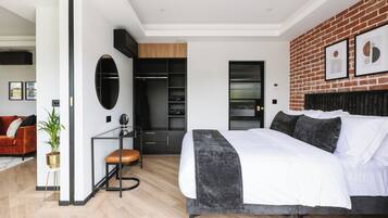A modern bedroom with a large bed, a closet, and a seating area.