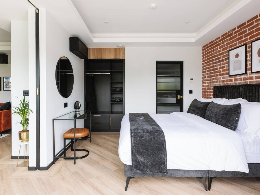 A modern bedroom with a large bed, a closet, and a seating area.