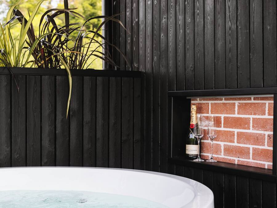 Ein Whirlpool mit Backsteinwand, einer Champagnerflasche und einem Glas.