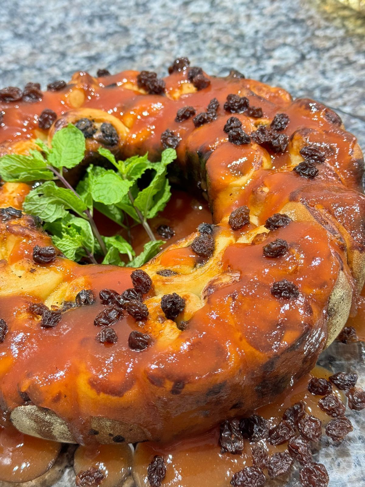 A close-up of a baked dish with raisins and mint leaves.