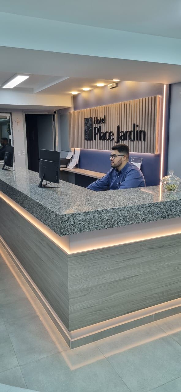 Un mostrador de recepción de diseño moderno, con un cartel encima y una persona sentada detrás.