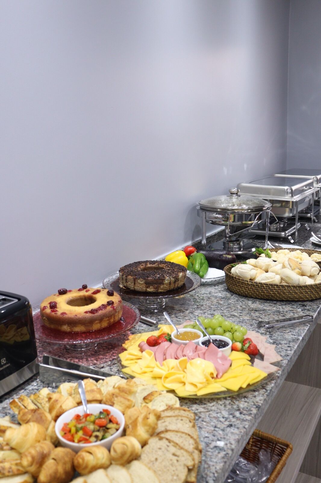A buffet with various food items including pastries, fruits, and cheeses.