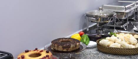 A buffet with various food items including pastries, fruits, and cheeses.