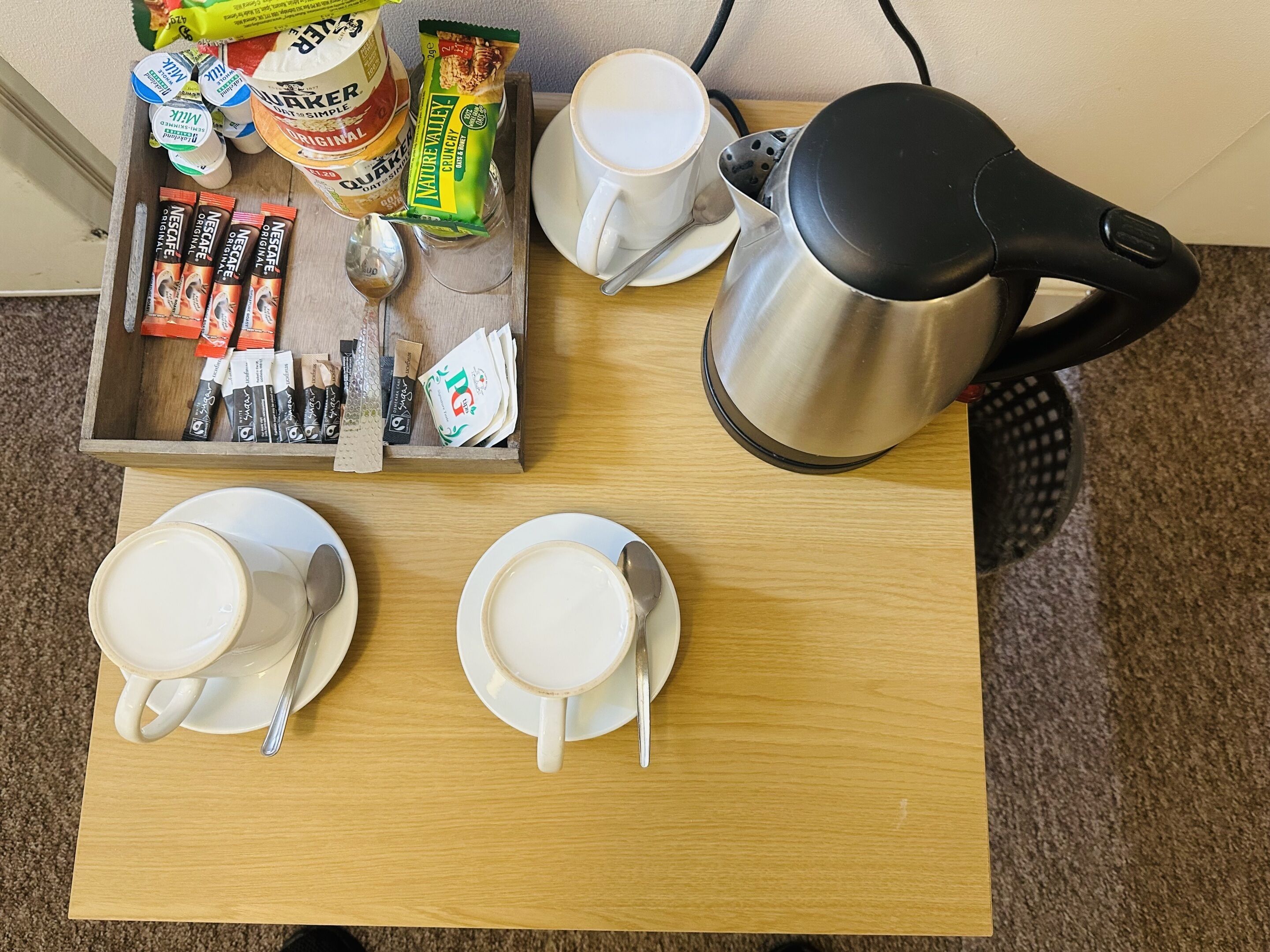 Bandeja de desayuno con café, té y aperitivos sobre una mesa de madera.