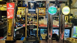 A bar with multiple taps including Kingfisher, Guinness, Carlsberg, and Cobra. - Woodcock Inn (East Grinstead)