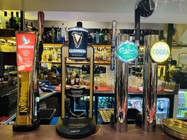 Un bar con varias opciones de cerveza, incluyendo Kingfisher, Guinness, Carlsberg y Cobra.