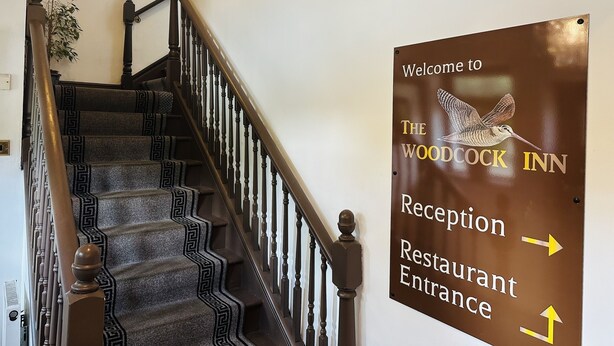 A staircase with a sign indicating the reception and restaurant entrance of The Woodcock Inn. - Woodcock Inn (East Grinstead)