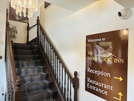 Una escalera con un letrero que indica la entrada de recepción y restaurante de The Woodcock Inn.
