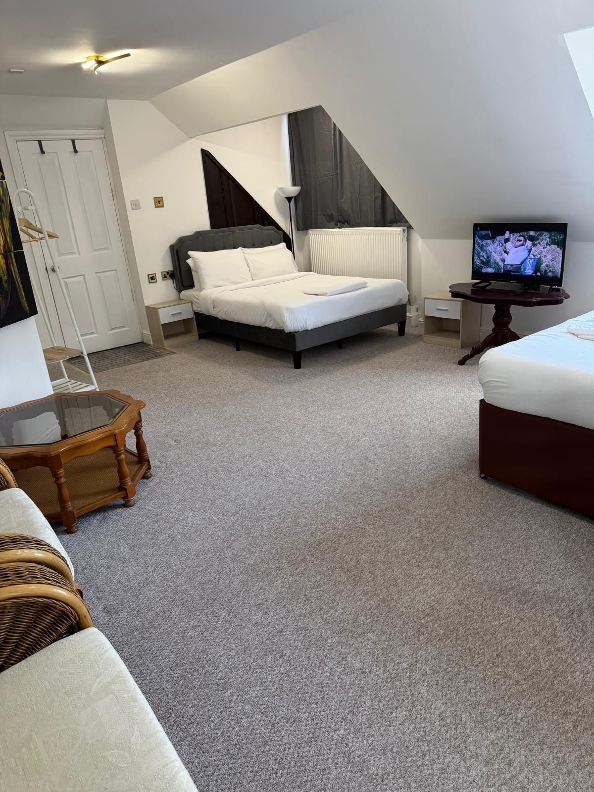 A bedroom with a bed, a television, a bedside table, a chair, and a window with curtains.