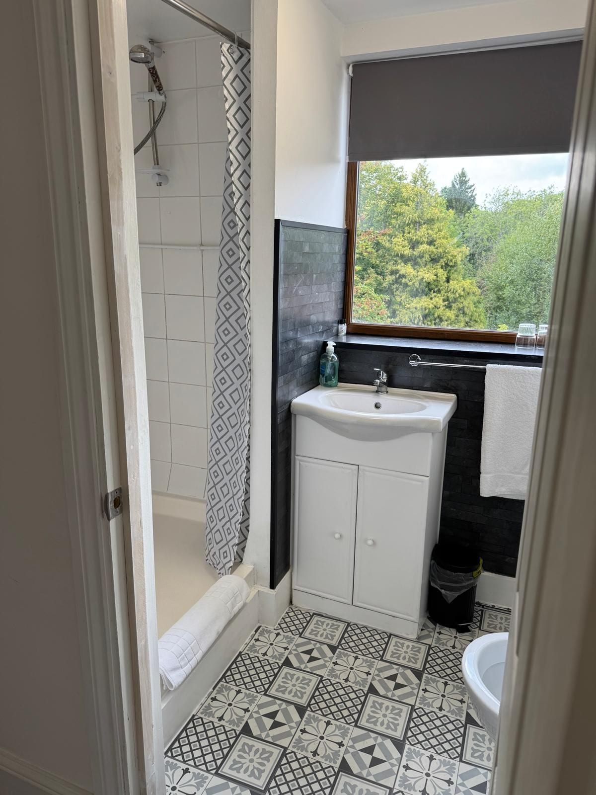 Un baño con ducha, lavamanos y ventana.