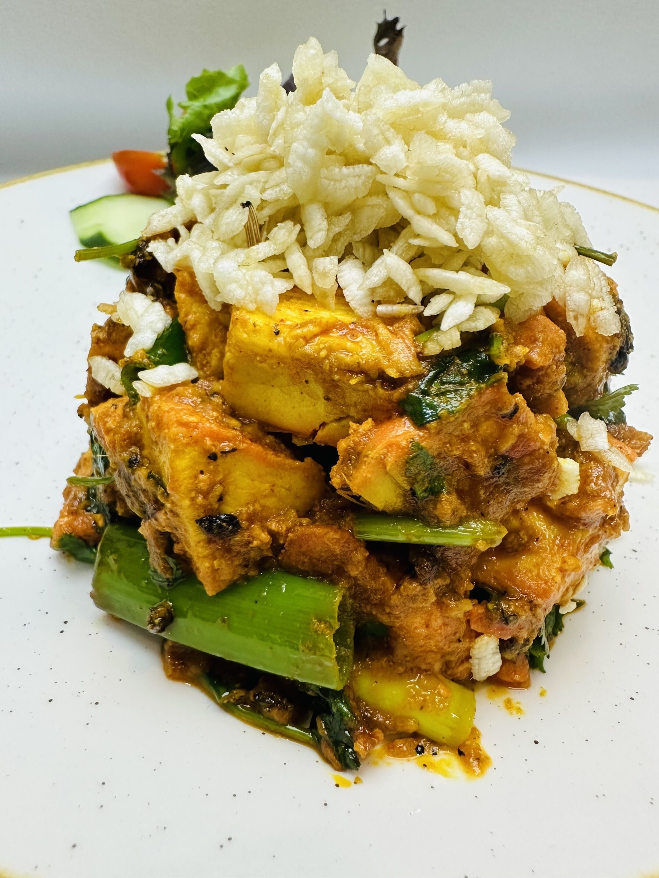 Une assiette de nourriture composée de riz, de poulet et de légumes.