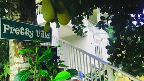 Uma escadaria com corrimão branco leva a um alpendre. Uma placa de rua diz "Pretty Wild".
