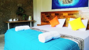 Quarto de hotel com uma cama grande, duas almofadas, mesa de cabeceira com planta e uma obra de arte na parede.