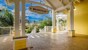 A covered outdoor area with a sign reading "Beach Club" and palm trees in the background.