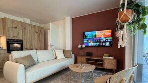 En moderne stue med sofa, sofabord og et fladskærms-tv monteret på væggen.