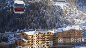 A multi-story hotel with balconies, surrounded by snow-covered mountains and ski lifts. - Wifi, ski-in/ski-out & foot of the slopes, swimming pool, balcony, tv, ski locker, 75-80m², Tignes (Tignes)