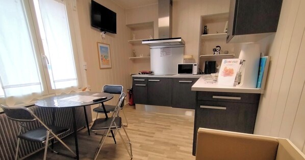 Eine moderne Küche mit Essbereich, einem Fernseher und einer Couch.