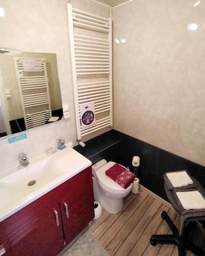 Ein Badezimmer mit einem weißen Waschbecken, einer roten Kommode, einer Toilette und einem kleinen Holzstuhl.