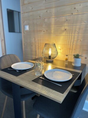 A dining table with two plates, a glass, and a candle. - Appartement au Centre Ville (Bruyères)