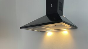 Una cuina moderna amb fogó d'inducció negre, forn integrat, campana extractora d'acer inoxidable i taulell de fusta.