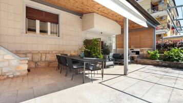 An outdoor patio with a stone wall, a wooden ceiling, and a table with chairs.