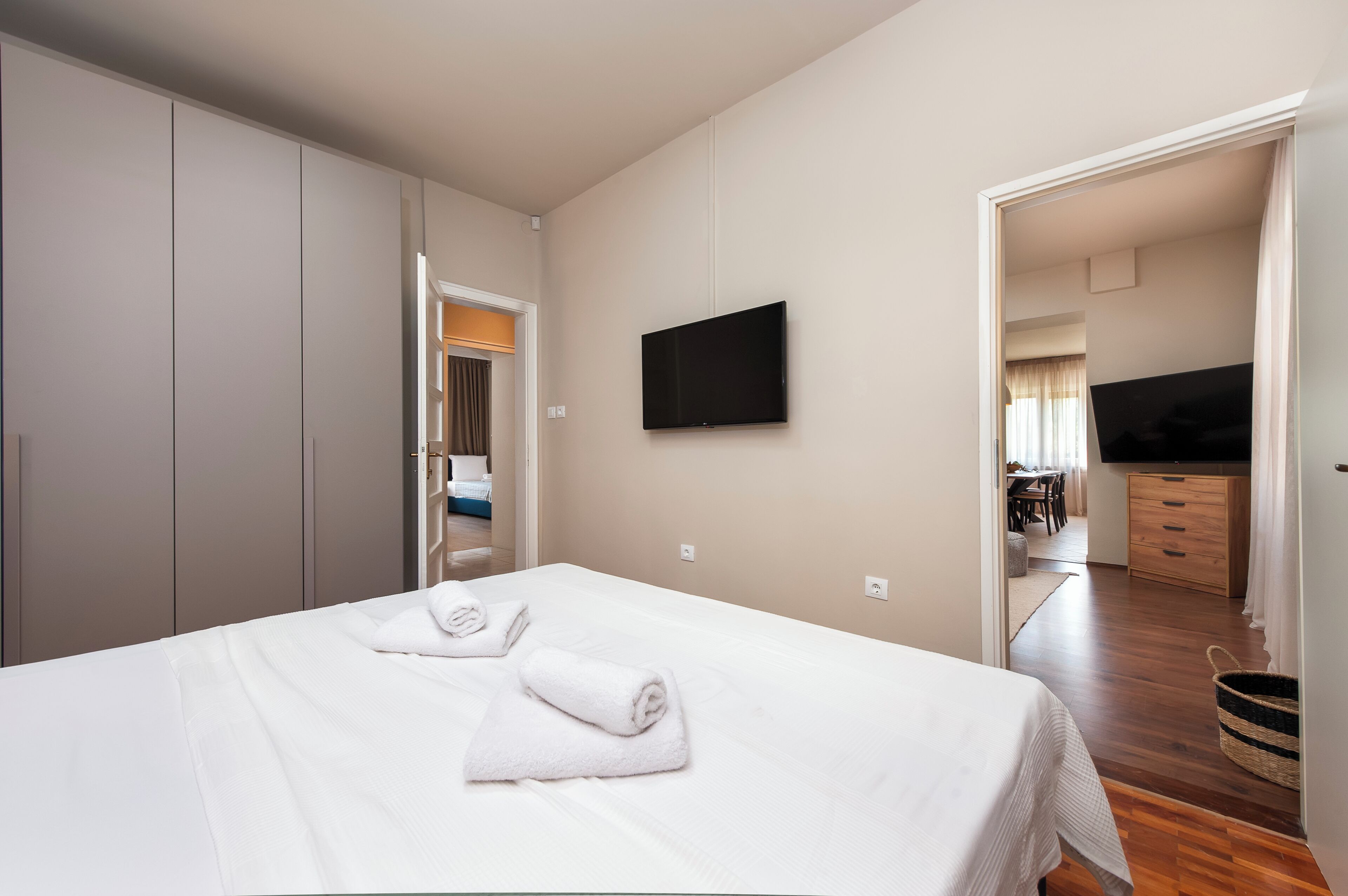 Een hotelkamer met een bed, een flatscreen televisie, een kledingkast en een badkamer zichtbaar door een open deur.