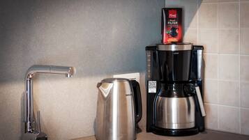 Een keuken met een koffiezetapparaat, waterkoker en waterfilter.