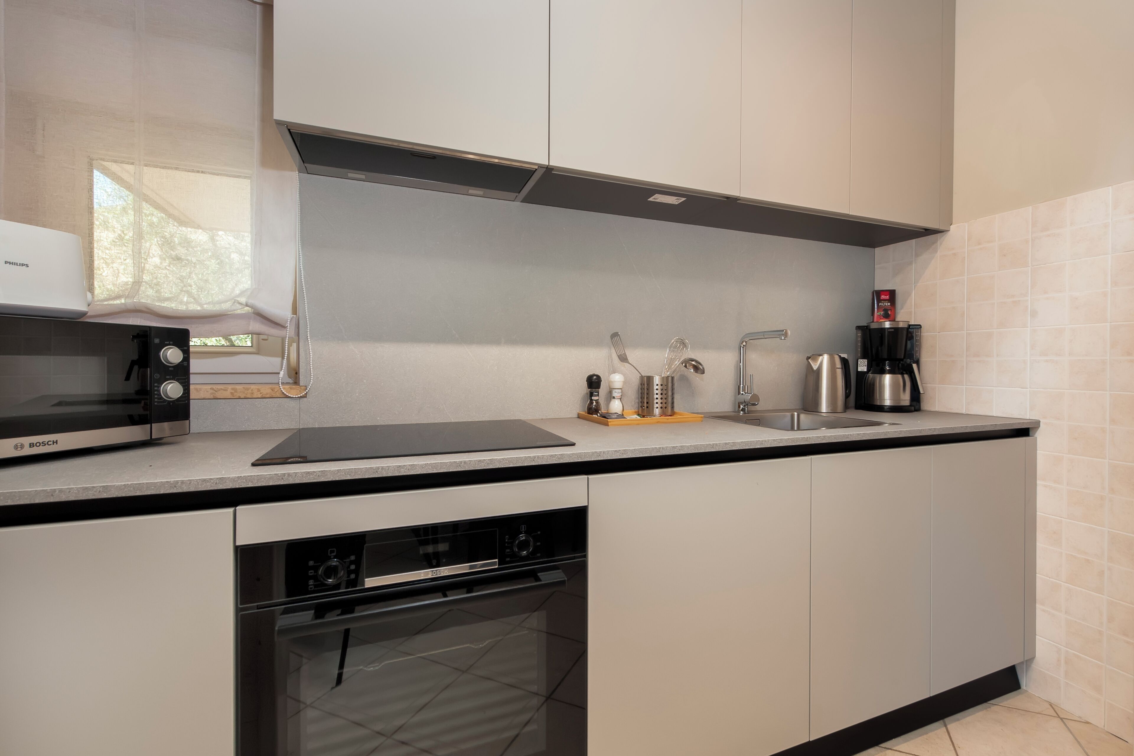 Eine moderne Küche mit Geräten von Bosch, einem eingebauten Backofen und einer Kaffeemaschine.