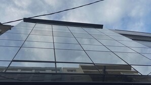 A modern building with a glass facade reflecting the sky. - Pel Apart Hotel  (Pelotas)