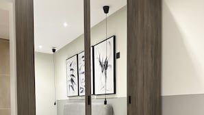 A modern bedroom with a bed, bedside tables, and artwork on the wall. - Kease Malqa D-1 Royal Touch  AX37 (Riyadh)