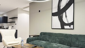 A modern living room with a green sofa, a white armchair, and a coffee table. - Kease Malqa D-1 Royal Touch  AX37 (Riyadh)
