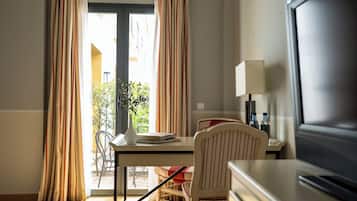 Habitación de hotel con una mesa de comedor, sillas, televisor y lámpara.
