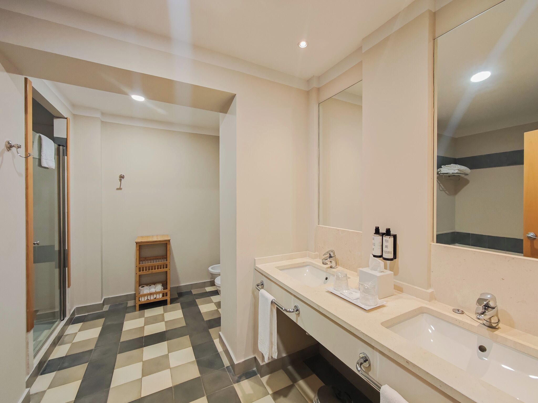 Une salle de bain moderne avec deux lavabos, un grand miroir et un espace douche.