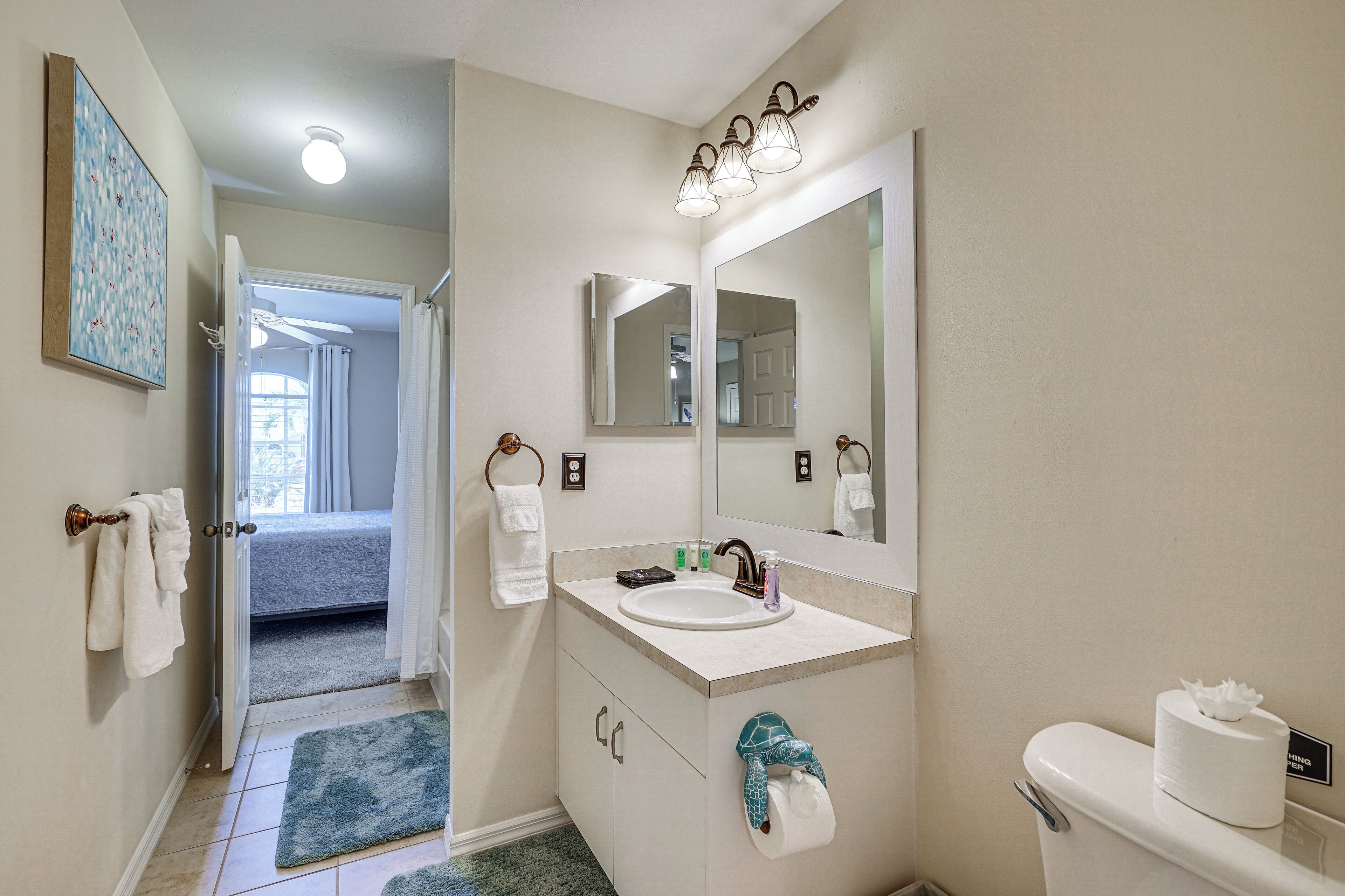 A bathroom with a sink, mirror, toilet, and a towel rack.