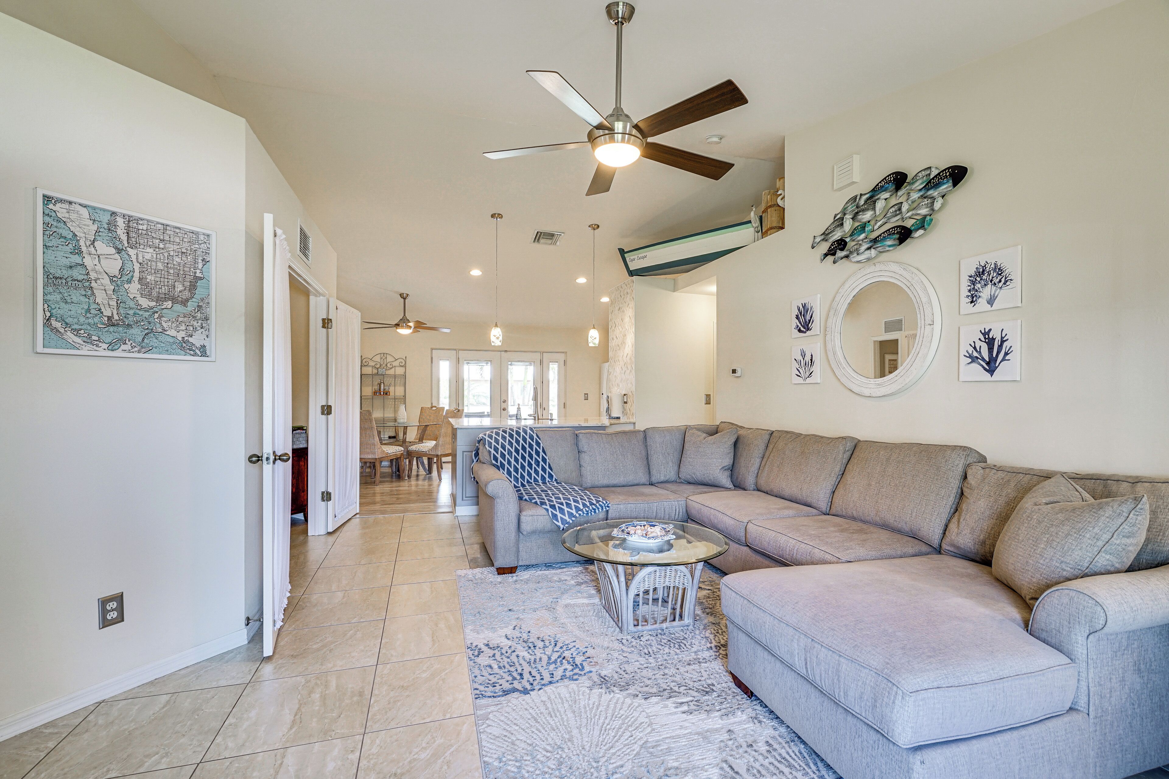 A spacious living room with a large sectional sofa, a dining area with a table and chairs, and a kitchen in the background.