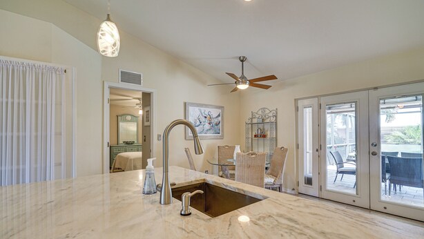 A kitchen with a marble countertop, a sink, and a ceiling fan.