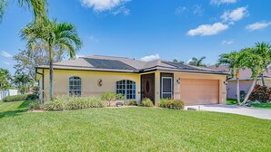 A single-story house with a garage, a well-maintained lawn, and a clear blue sky.