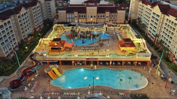 A hotel with a central pool, multiple water slides, and a large outdoor area.