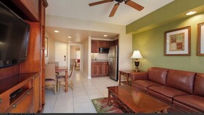 A living room with a television, a sofa, a coffee table, and a ceiling fan.