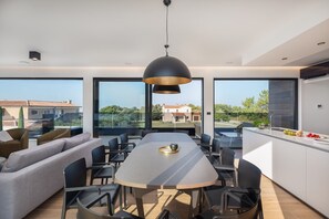 Een moderne keuken met een eethoek, grote ramen en uitzicht op de omgeving.