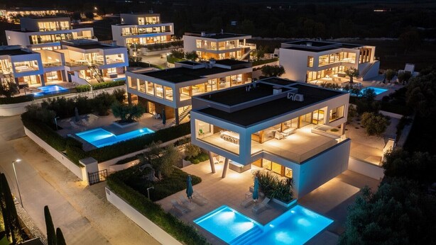 A modern multi-story residential complex with multiple swimming pools and well-lit outdoor areas. - Luxury villa with swimming pool and sauna near Pula. (Vodnjan)