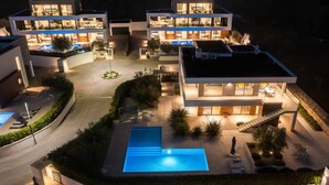 A modern multi-story house with a swimming pool, outdoor seating, and a well-lit driveway. - Luxury villa with swimming pool and sauna near Pula. (Vodnjan)