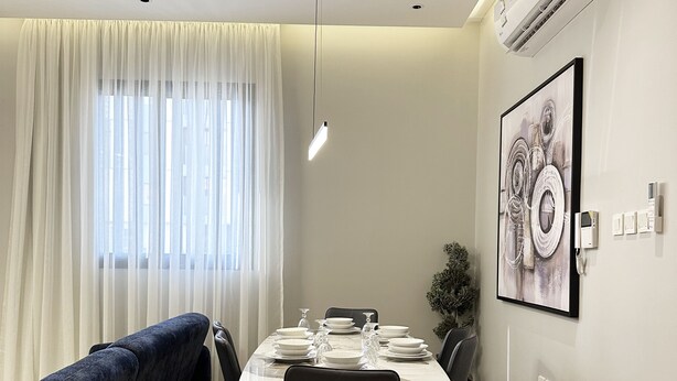 Ein moderner Essbereich mit einem Tisch für vier Personen, einer Couch und einem großen abstrakten Gemälde an der Wand.