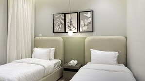 Ein Hotelzimmer mit zwei Betten, einem Nachttisch mit Telefon und Wandbildern.